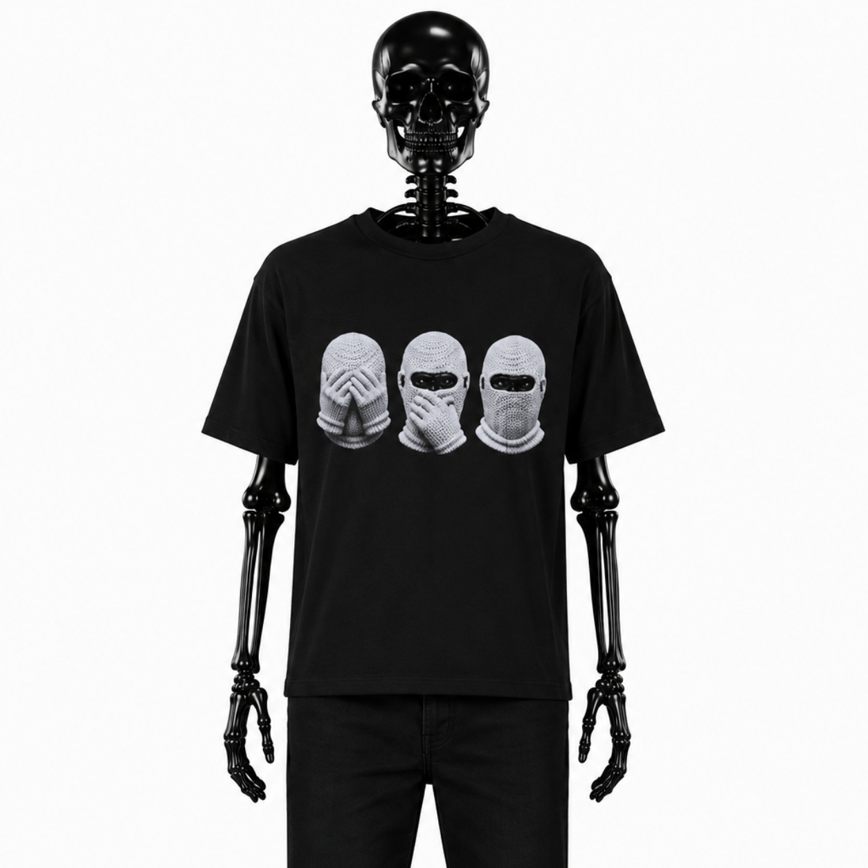 Image de l'avant du t-shirt "Omerta" de Gotham Mahtgo. Ce t-shirt est noir et sur l'avant 3 singes sont floqués. Les 3 singes ont des cagoules blanches, un à ses mains devant ses yeux, le 2ème les mains devant sa bouche et le 3ème à des croix sur ses oreilles. Mannequin : Squelette de face